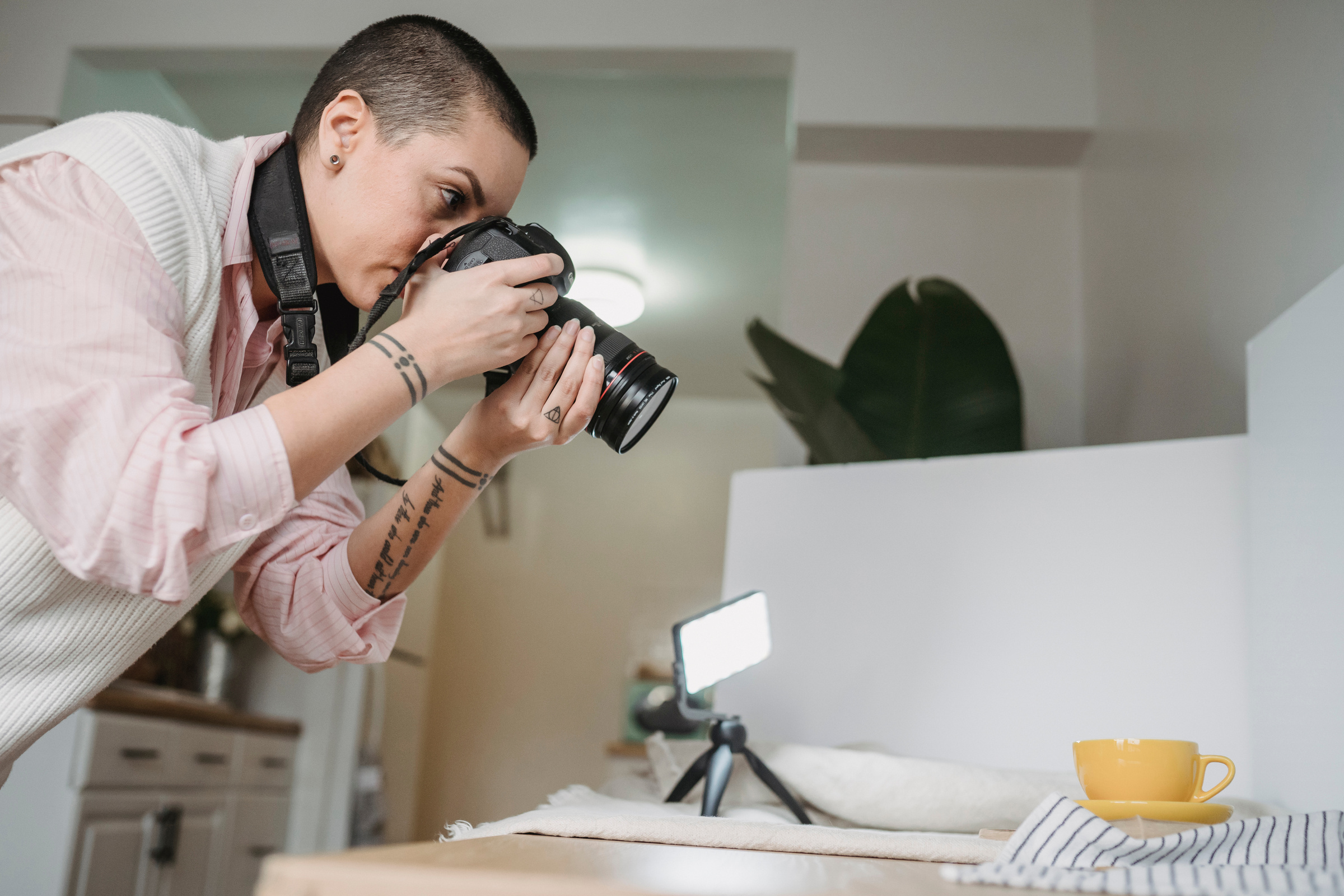 Photographer taking photo of cup on professional camera in kitchen
