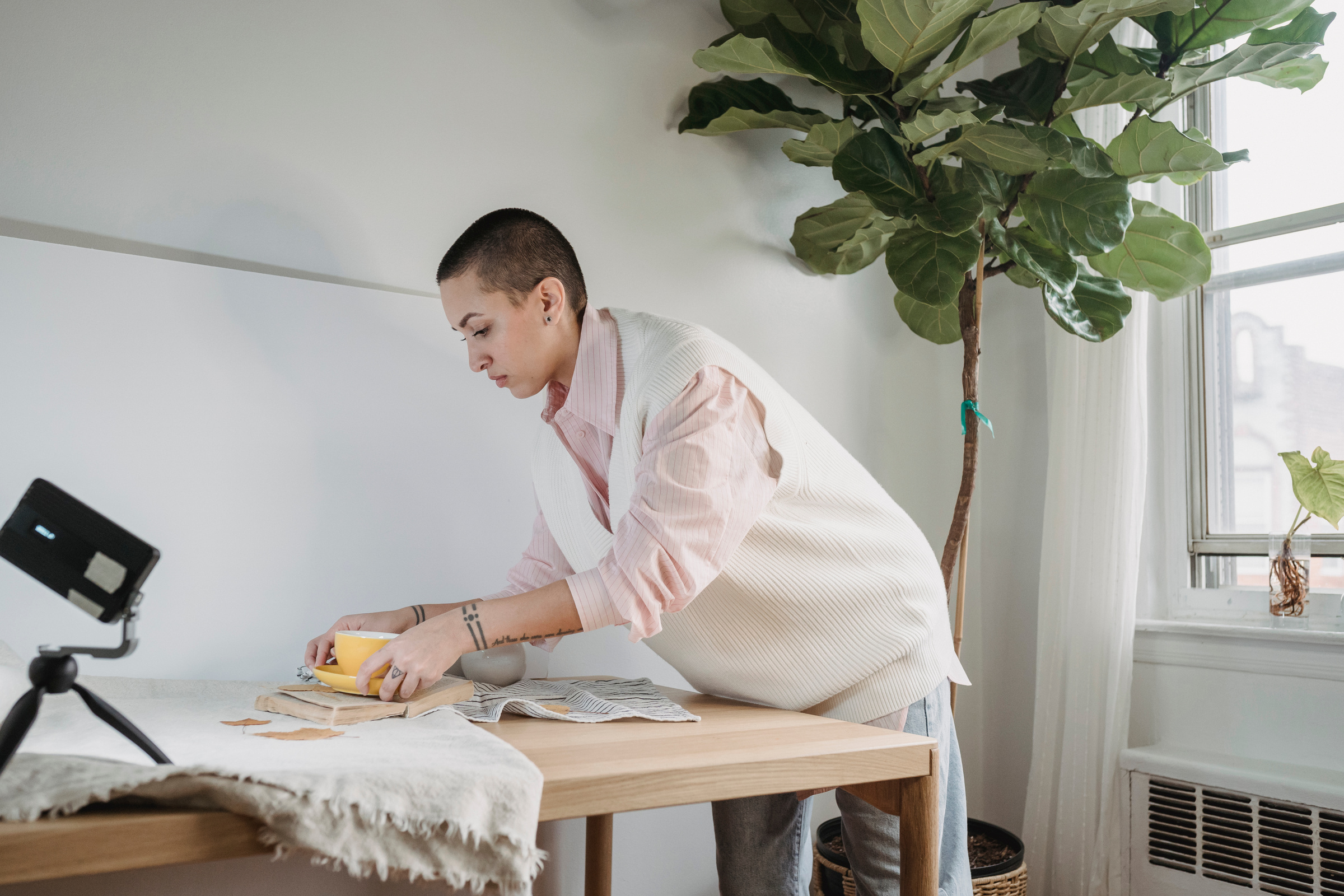 Focused short haired female photographer placing cup on opened book